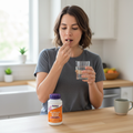 Pessoa adulta a tomar uma cápsula Mushroom Immune Renew com água numa rotina diária